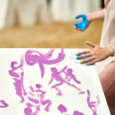 Woman hand smearing blue paint on canvas, art expression at outdoor art festival, art improvisation